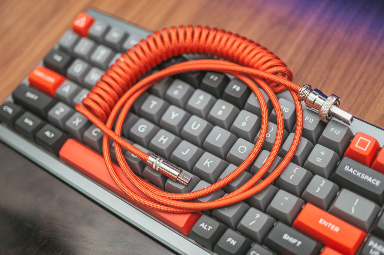 services-03 Close-up of a custom coiled cable resting on a mechanical keyboard, showcasing modern technology aesthetics.